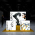 A frontal view of the Pixlip GO booth, emphasizing its modern and technological theme. The main backdrop displays a robotic arm and a cyber-themed woman, while the counters in front feature detailed images of robotic and mechanical hands. The yellow floor contrasts with the clean white lighting of the displays.